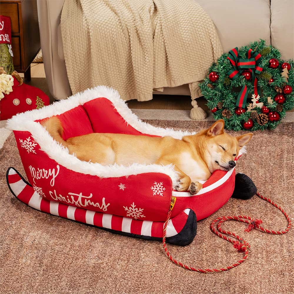 Christmas-themed dog bed in sleigh design featuring soft red fabric and decorative rope accents.
