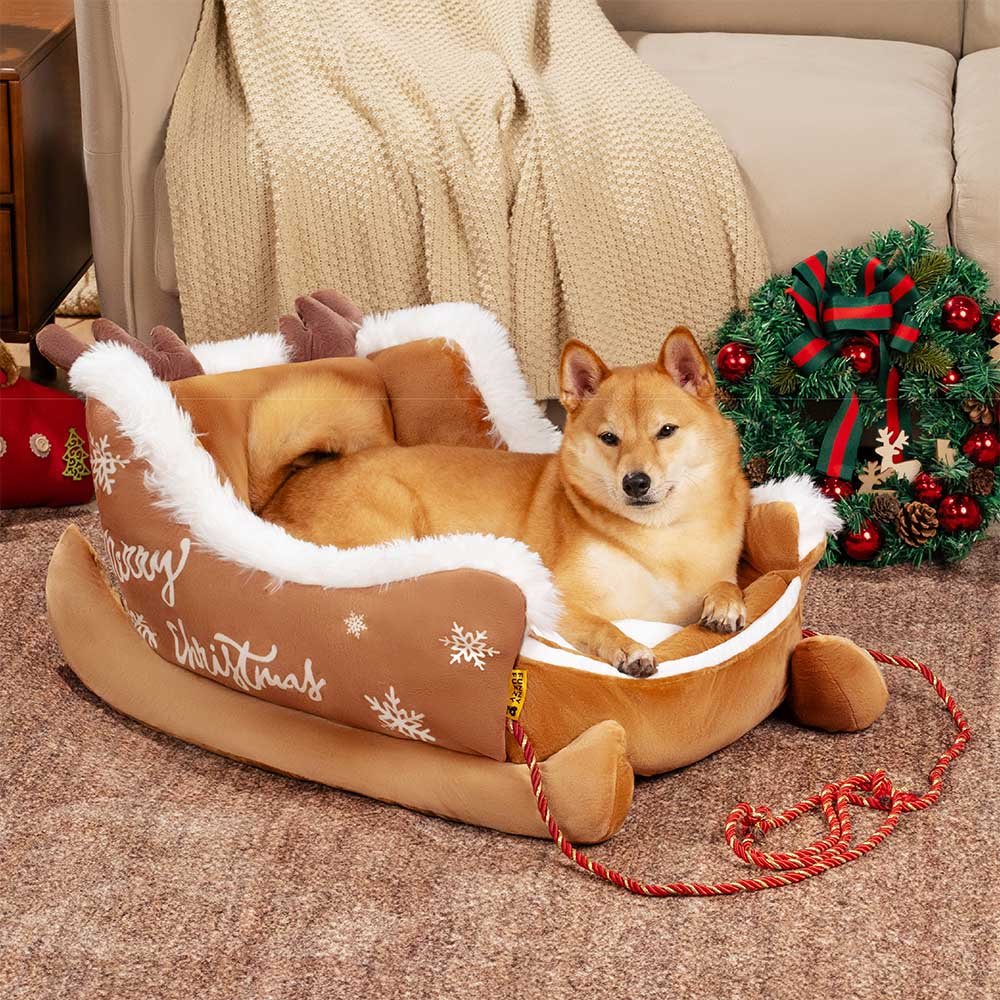 Christmas-themed dog bed in sleigh design featuring soft red fabric and decorative rope accents.