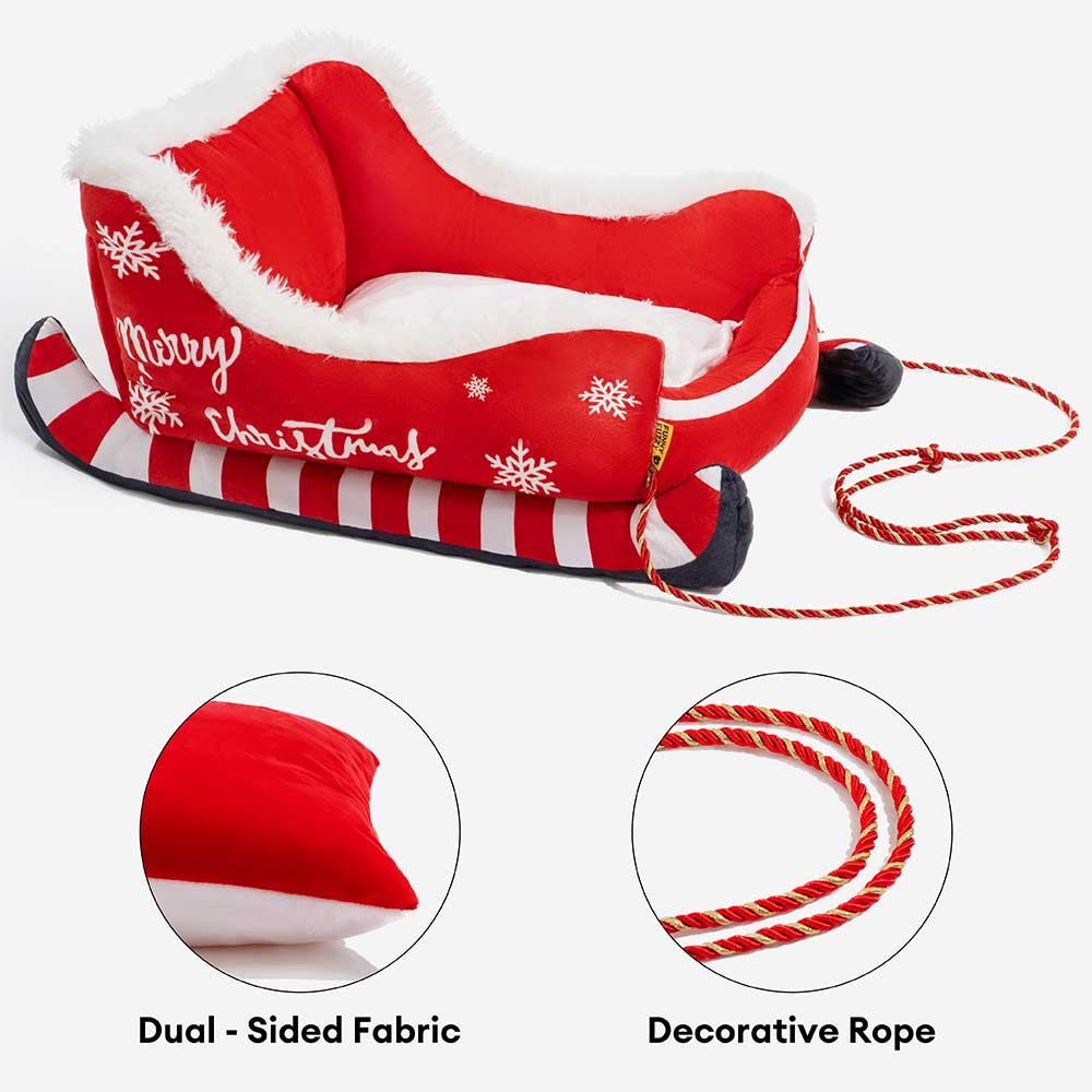 Christmas-themed dog bed in sleigh design featuring soft red fabric and decorative rope accents.